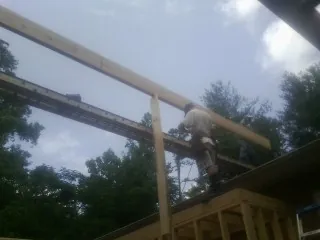 Carpenter setting a ridge beam over a new addition frame — Ice Dam Removal by Roofing Brothers in Madrid