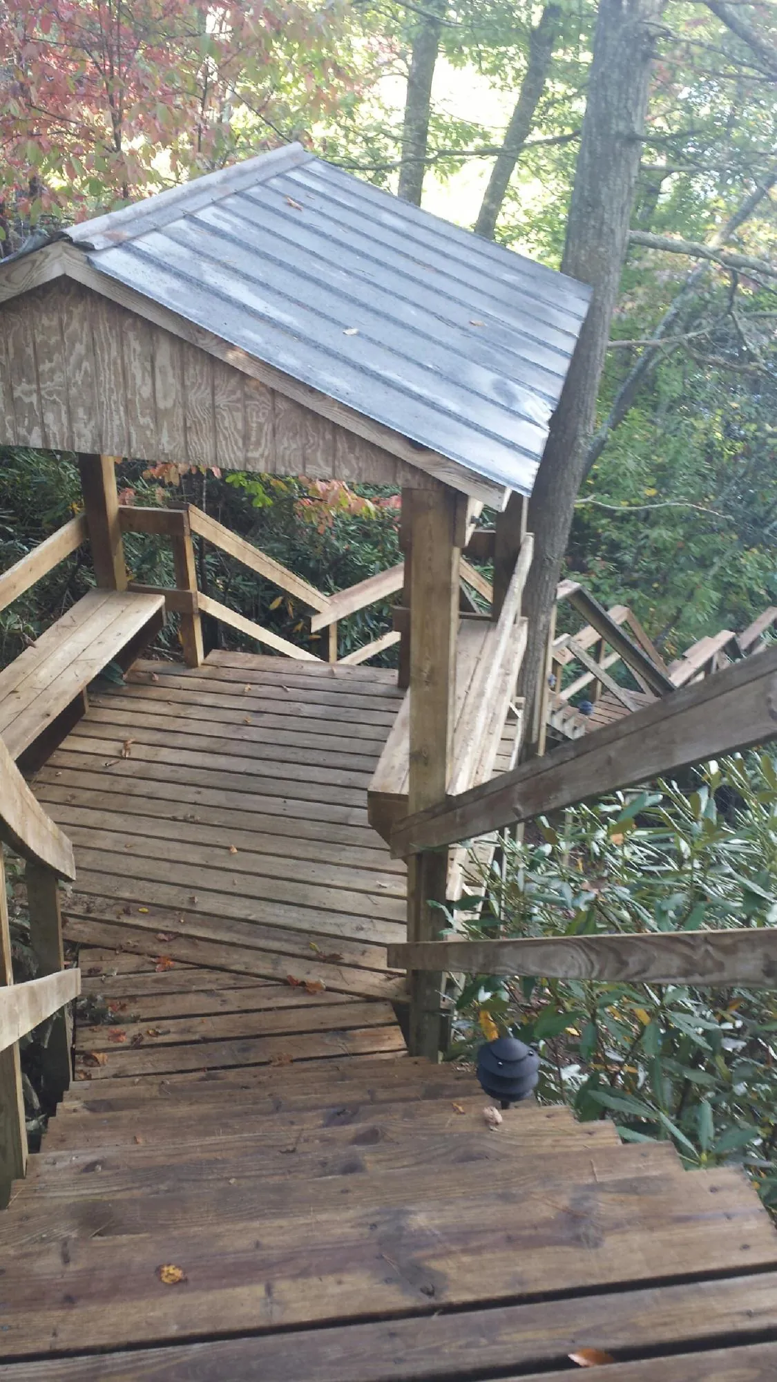Metal roofed shelter over wooden steps on a wooded walkway — Skylight Repair & Installation work by our crew in Madrid