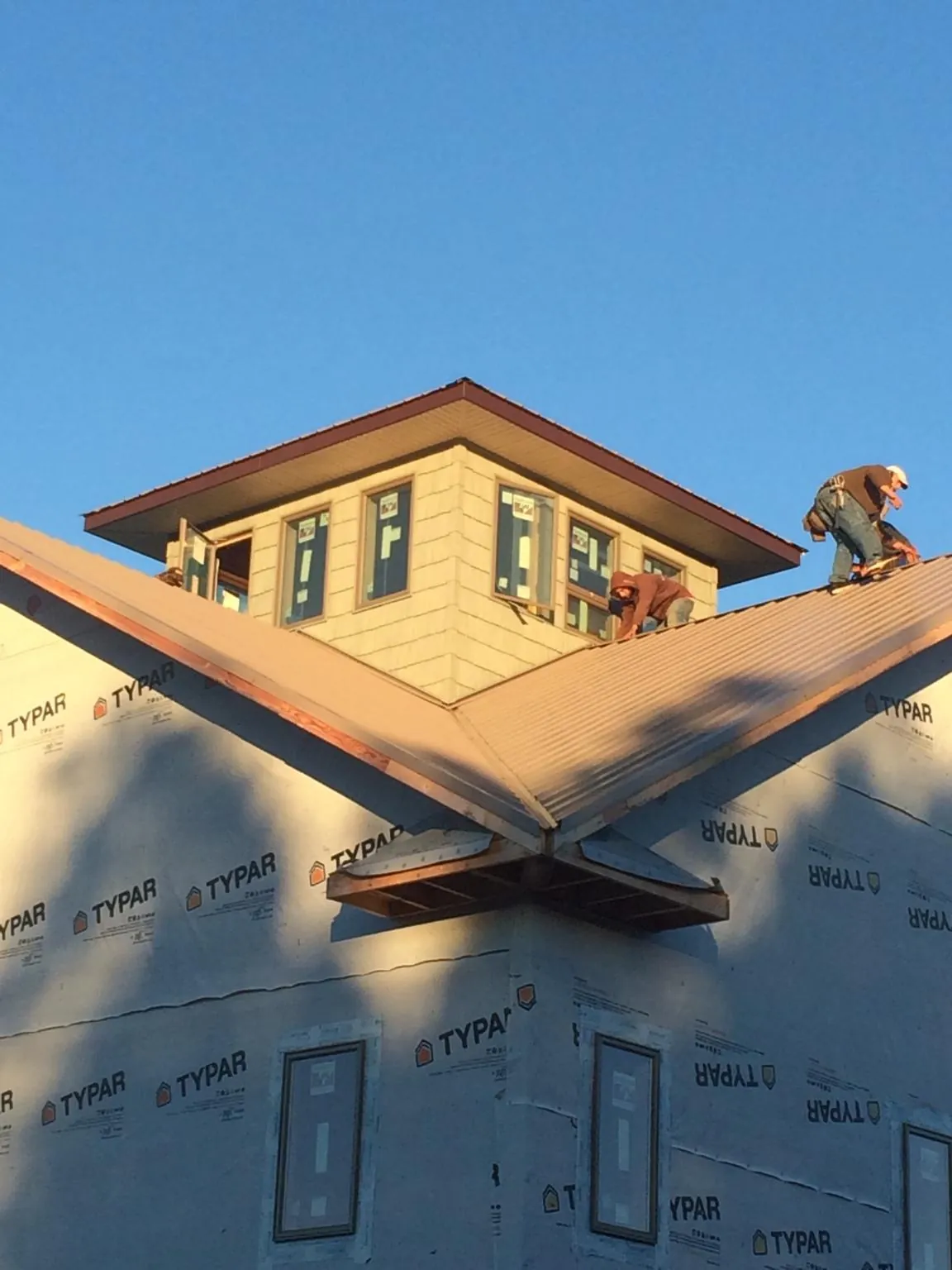 Roofers working around a rooftop cupola on a new metal roof at sunset — Roof Waterproofing in Madrid by Roofing Brothers